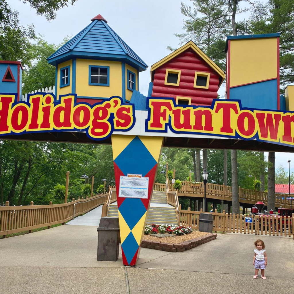 HoliBlogger Tara's daughter next to the Holidog's FunTown entrance sign