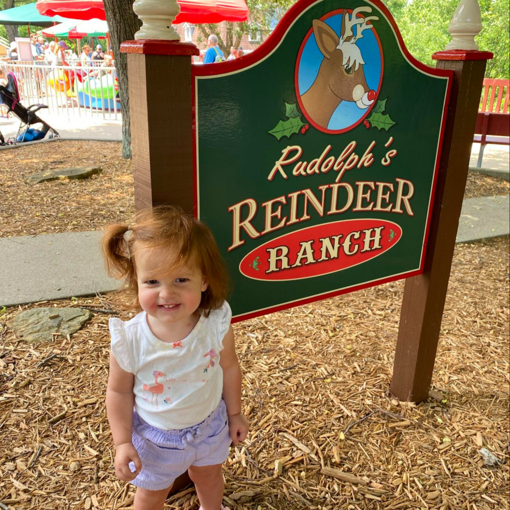 HoliBlogger Tara's daughter next to the Reindeer Ranch sign