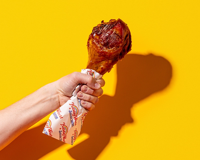 A hand holding a turkey leg that is wrapped in deli paper at Holiday World & Splashin' Safari in Santa Claus, Indiana.