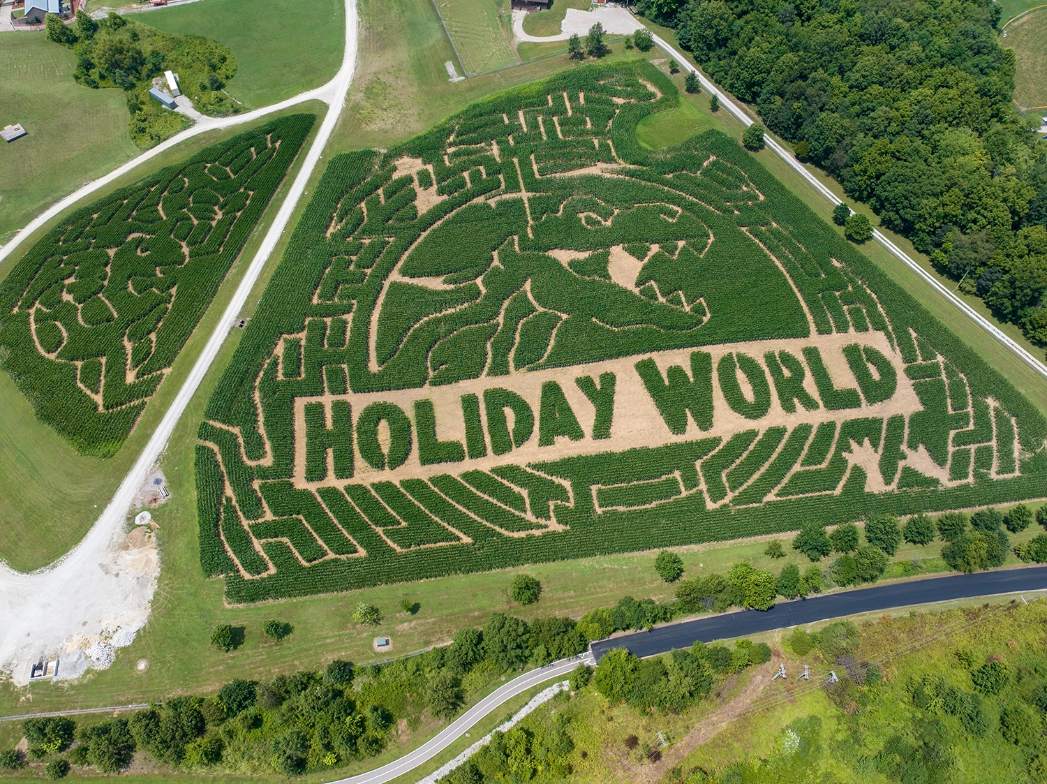Aerial view of the 2025 Happy Halloween Weekends Corn Maze featuring an image of a T-Rex and the words "Holiday World" cut into the cornfield.