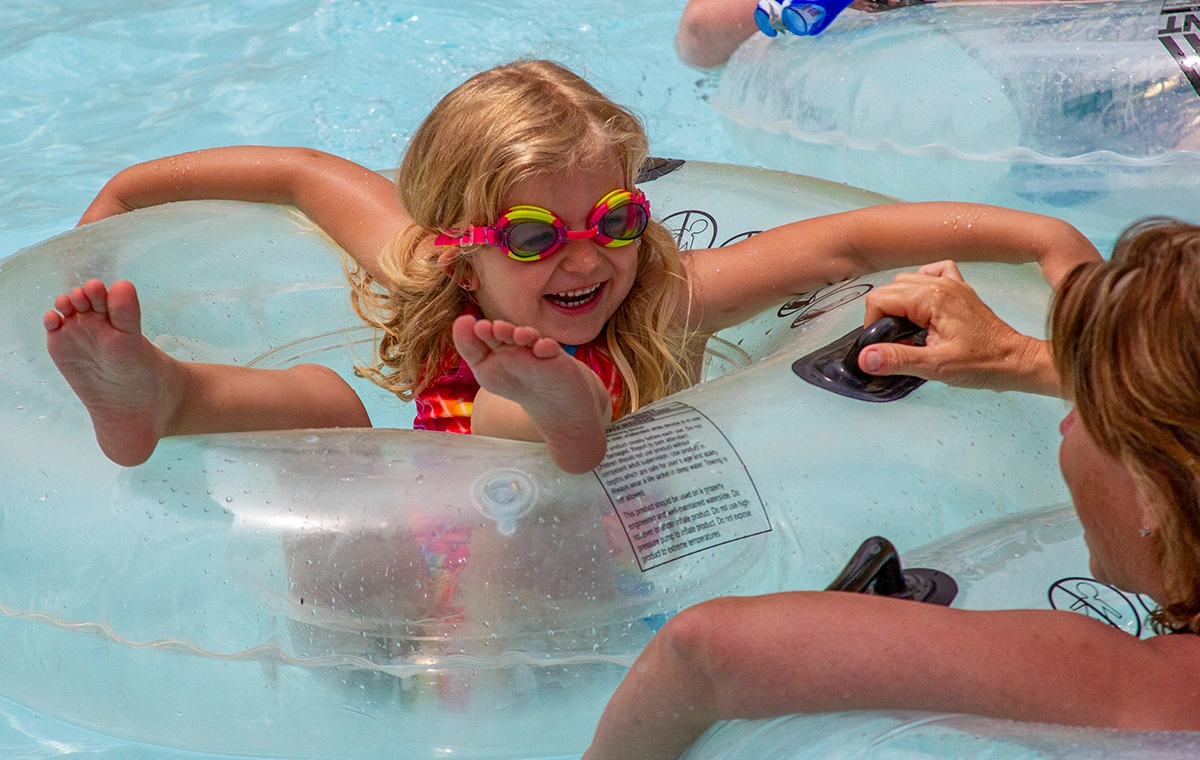 A smiling young girl with goggles on an innertube on Bahari River lazy river at Holiday World & Splashin' Safari in Santa Claus, Indiana.