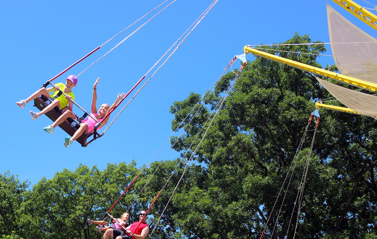 A girl swings with her arms raised on Crow's Nest at Holiday World & Splashin' Safari in Santa Claus, Indiana.