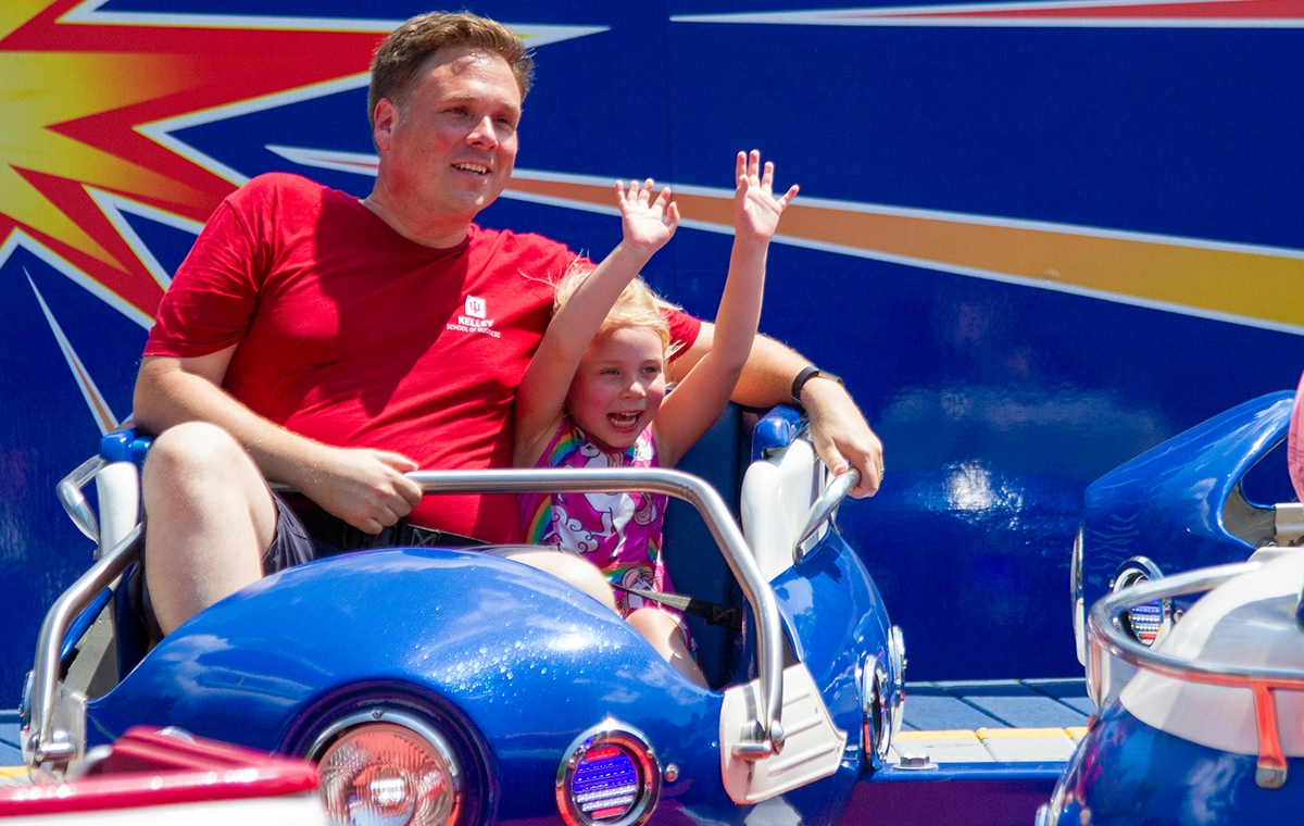 A young girl rides with hands up next to her dad on Firecracker at Holiday World & Splashin' Safari in Santa Claus, Indiana.
