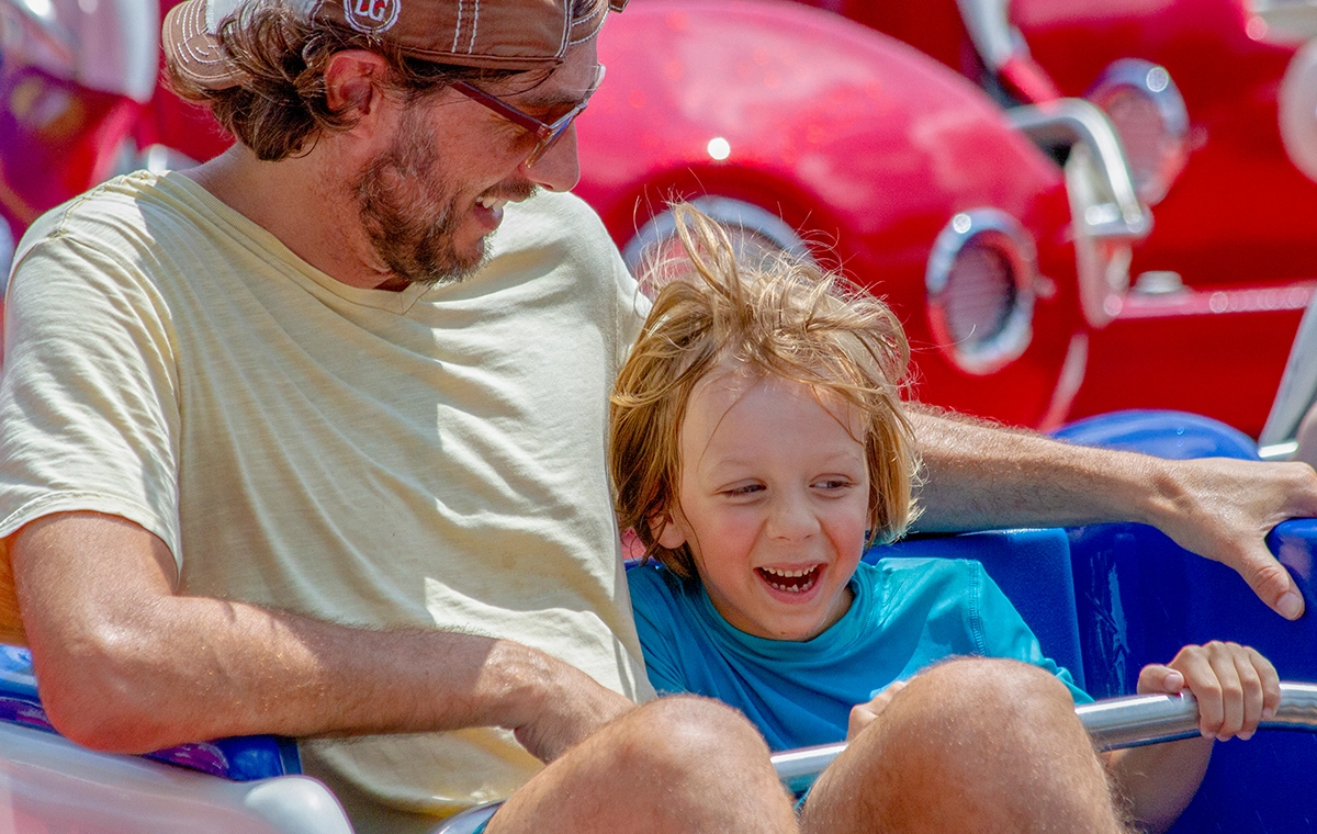 A father and son smile as they hang on while riding Firecracker at Holiday World & Splashin' Safari in Santa Claus, Indiana.