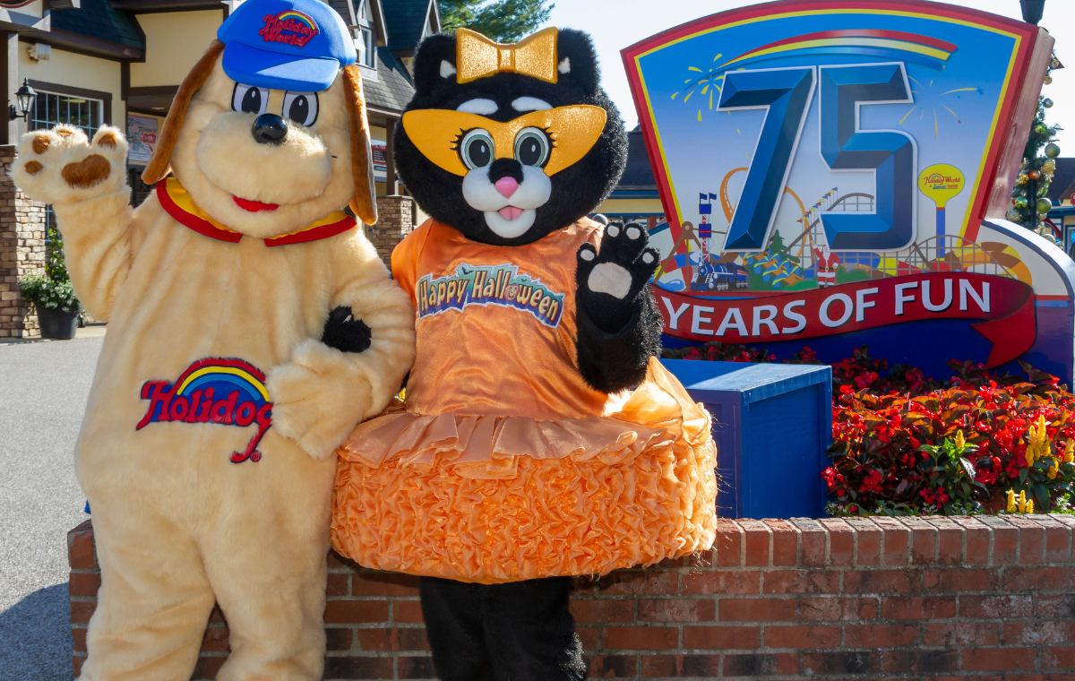 Holidog and Kitty Claws posing in front of the 75th anniversary sign