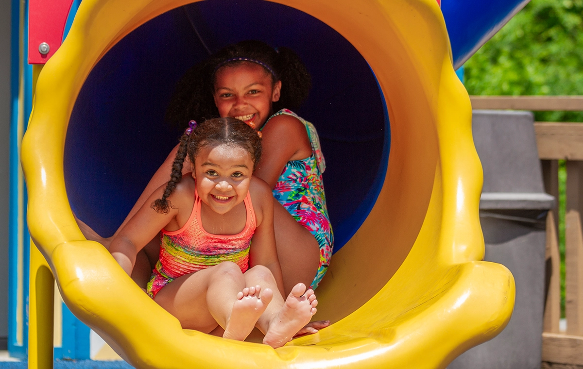 Two young girls have big smiles the bottomof the slide of Holidog's Treehouse at Holiday World & Splashin' Safari in Santa Claus, Indiana.