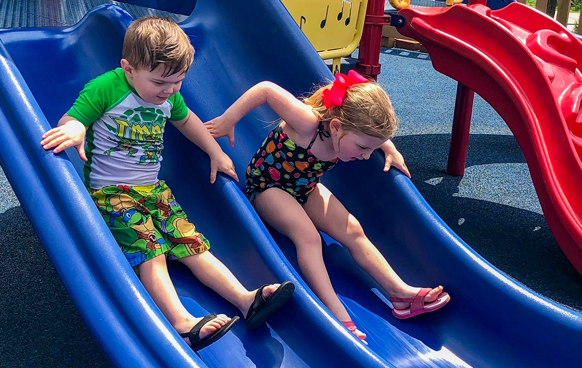 Two young children race down a slide of Just for Pups at Holiday World & Splashin' Safari in Santa Claus, Indiana.