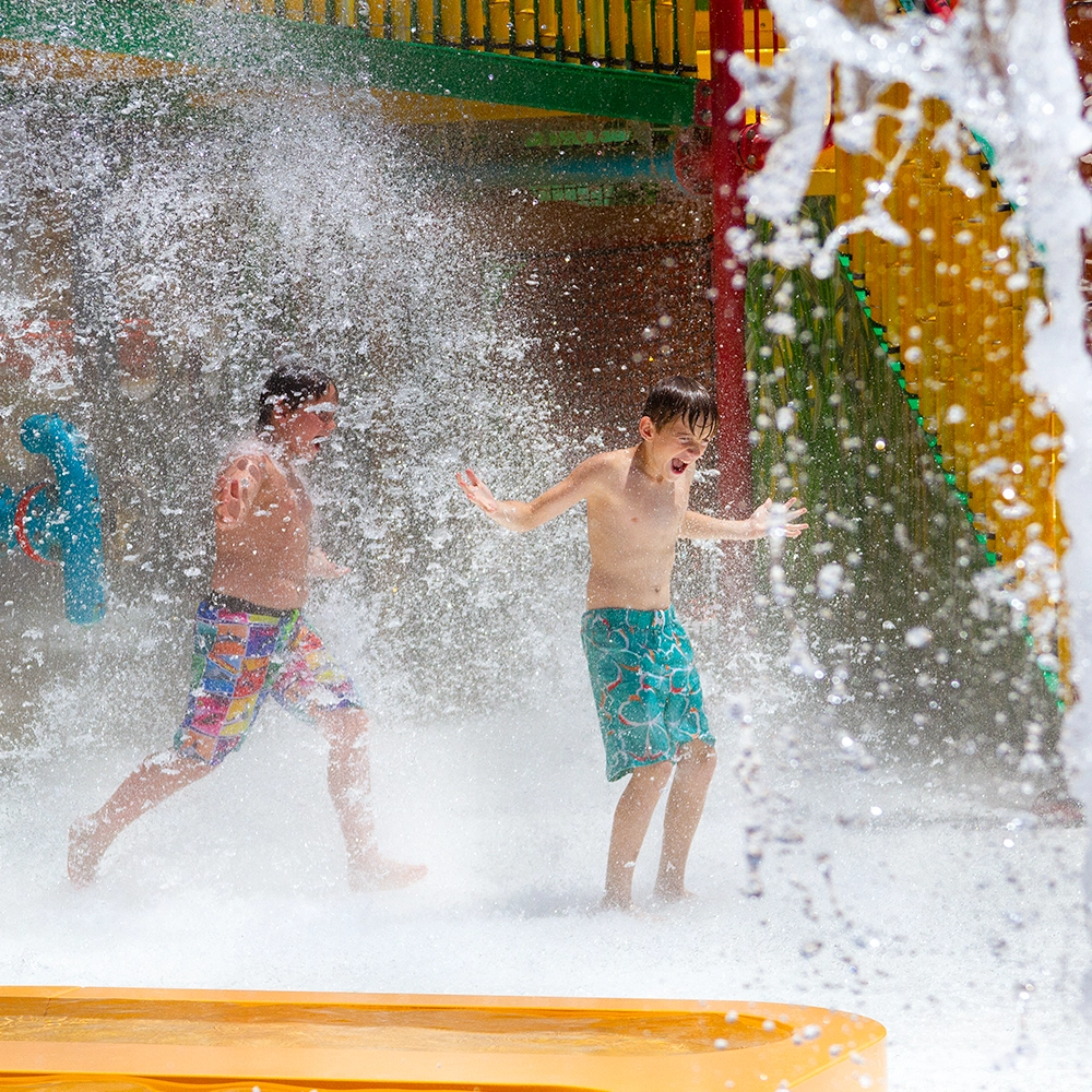 Boys getting splashed by the waterfall of Kima Bay at Holiday World & Splashin' Safari in Santa Claus, Indiana.