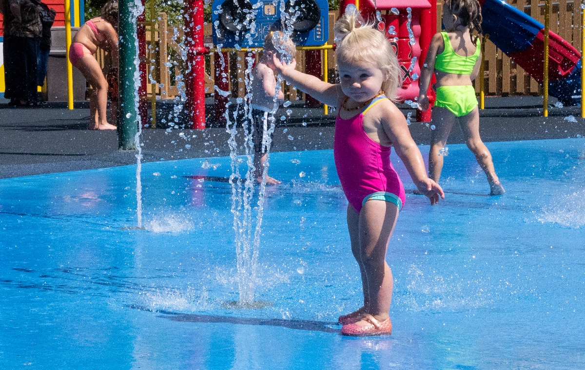 A small girl reaching out to touch a spray element in Magic Waters at Holiday World & Splashin' Safari in Santa Claus, Indiana.