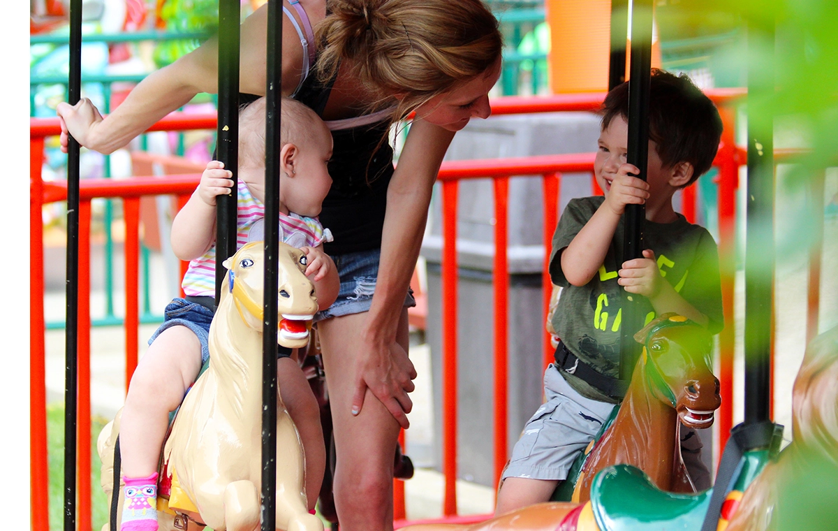 A mom talks to her son while helping an infant rider on Prancer's Merry-Go-Round at Holiday World & Splashin' Safari in Santa Claus, Indiana.