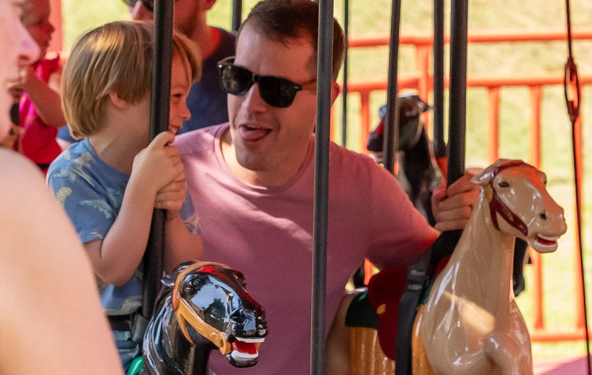 Young boy smiles as dad makes silly faces while riding Prancer's Merry-Go-Round at Holiday World & Splashin' Safari in Santa Claus, Indiana.