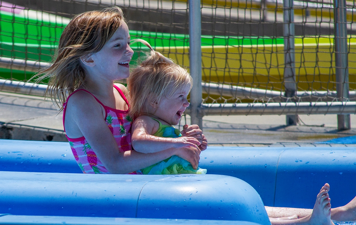 A young girl holds her toddler-aged sister on one of the eight slides of Safari Sam's SplashLand at Holiday World & Splashin' Safari in Santa Claus, Indiana.