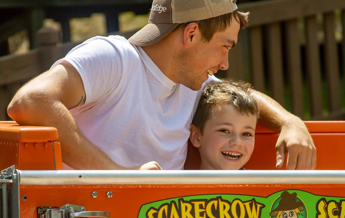 A father and young son have great smiles while riding Scarecrow Scrambler at Holiday World & Splashin' Safari in Santa Claus, Indiana.