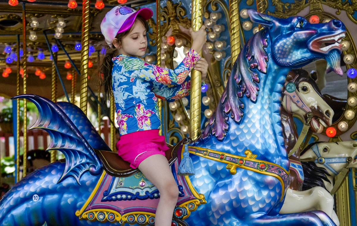 A young girl looks cautiously at the dragon she's riding on Star Spangled Carousel at Holiday World & Splashin' Safari in Santa Claus, Indiana.