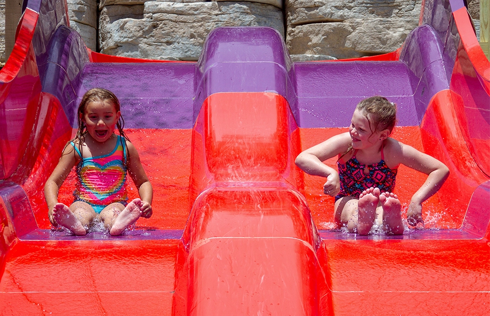 Two young girls race down a side-by-side slide at Tembo Falls at Holiday World & Splashin' Safari in Santa Claus, Indiana.