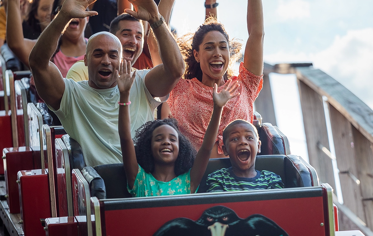 A family smiling and screaming down a hill on The Raven at Holiday World & Splashin' Safari in Santa Claus, Indiana