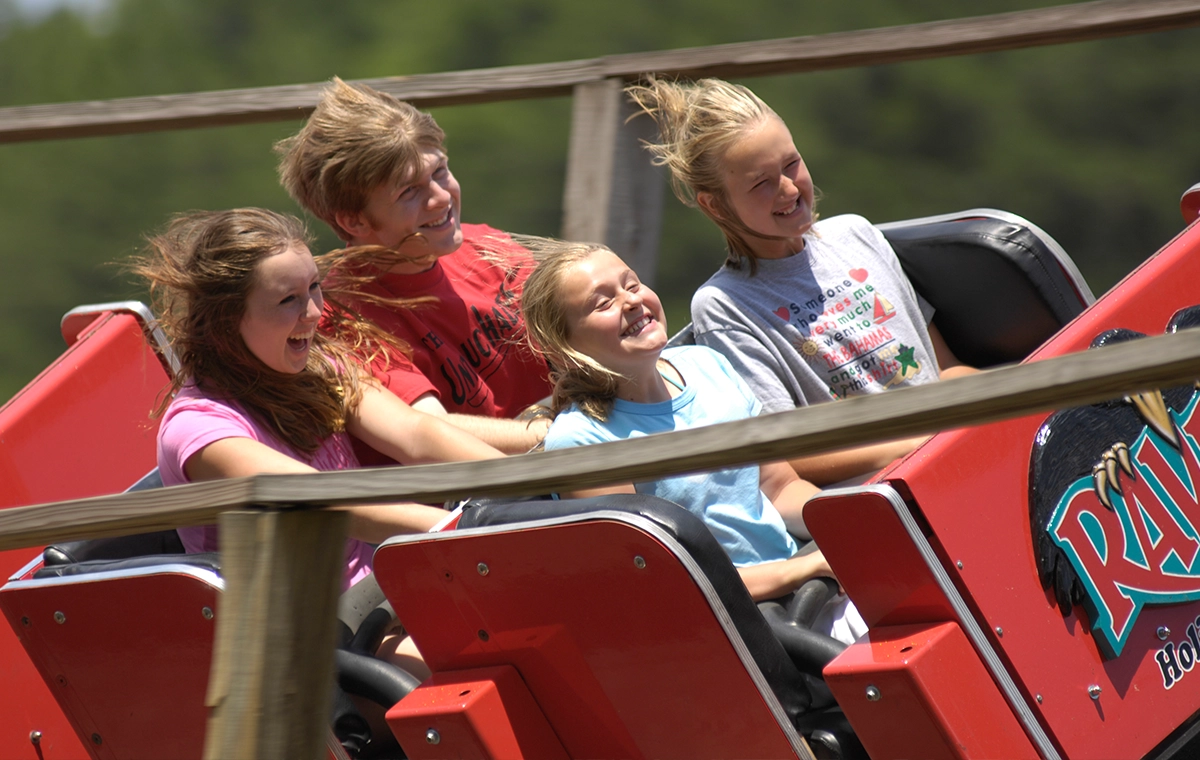 Four teenagers smiling and screaming while riding The Raven at Holiday World & Splashin' Safari in Santa Claus, Indiana