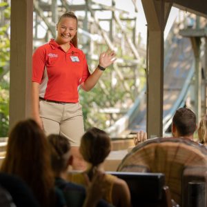 Holiday World Team Member smiling and waving at Guests who are on log flume attraction.