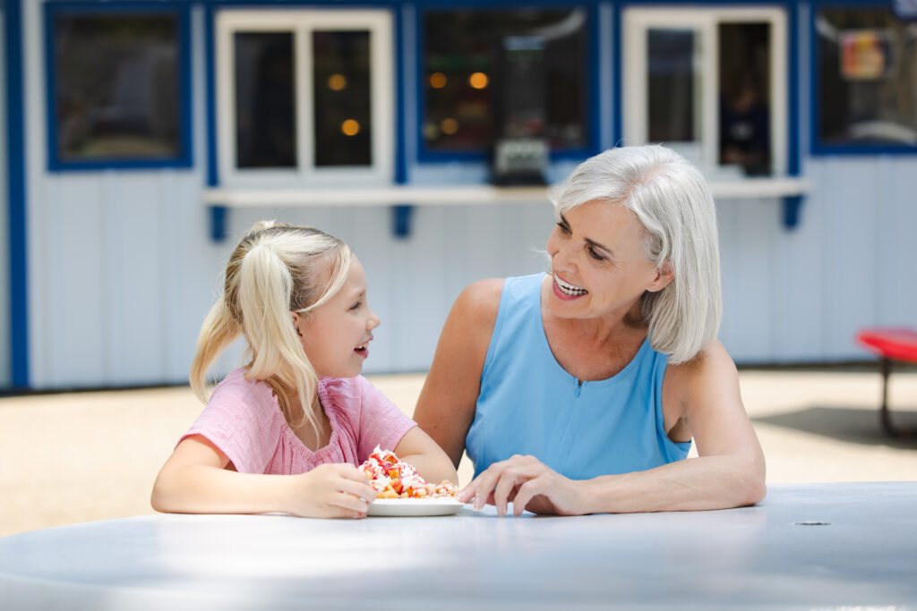 A little girl enjoying a funnel cake with her Grandmother at Freedom Funnel Cakes.