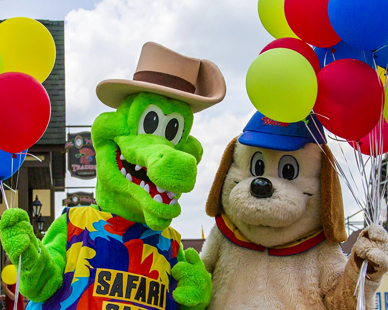 Safari Sam & Holidog carry balloons to celebrate Kids World.