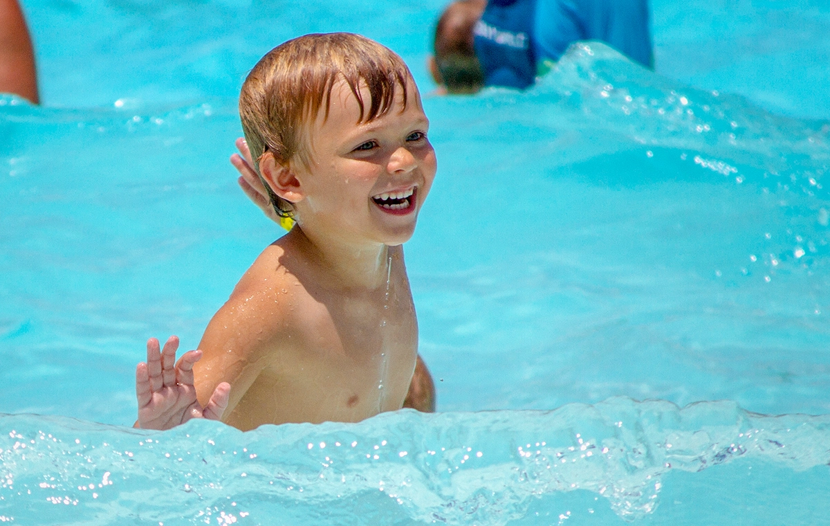Young boy smiling while playing in the waves of Bahari Wave Pool at Holiday World & Splashin' Safari in Santa Claus, Indiana.