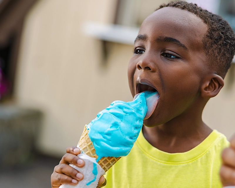 A young boy licks a tall "blue ice cream" from Udderly Blue.