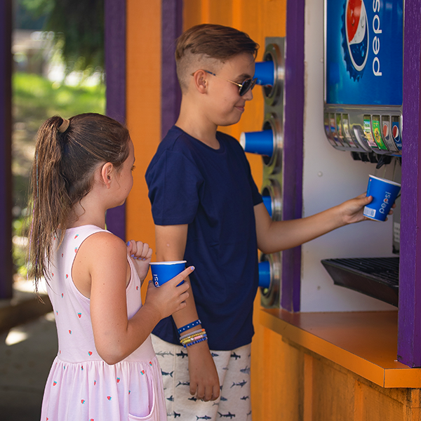 Two children at a free soft drink location filling a cup.