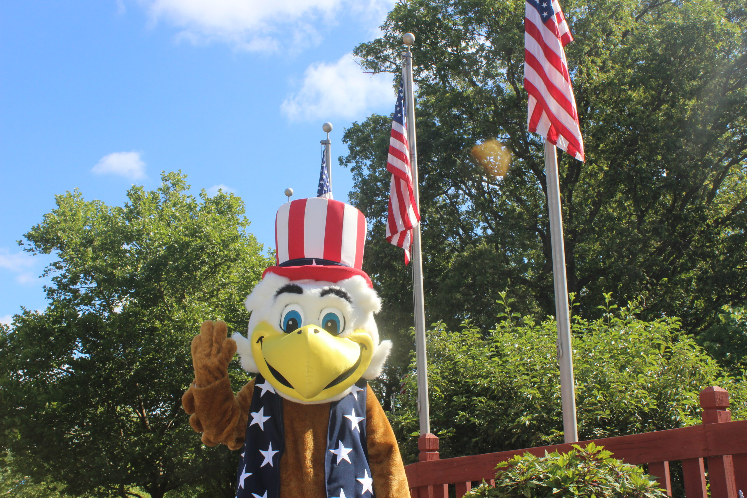 George The Eagle standing next to American Flags in the Fourth of July Section