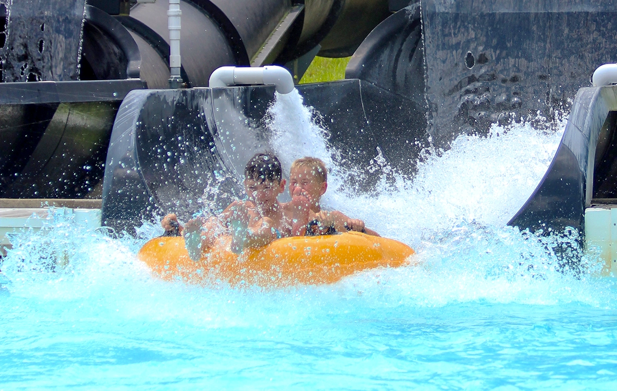Two young boys shooting out of the "Go" slide into the splashdown of Otorongo at Holiday World & Splashin' Safari in Santa Claus, Indiana.