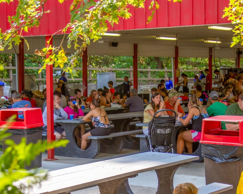 A large group eating a catered meal in a picnic shelter at Holiday World.