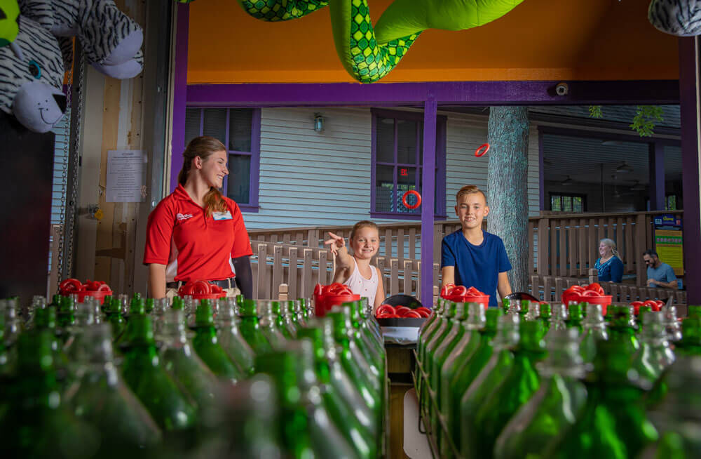 An employee watches a young girl try her chances at Raven's Ring Toss at Holiday World.
