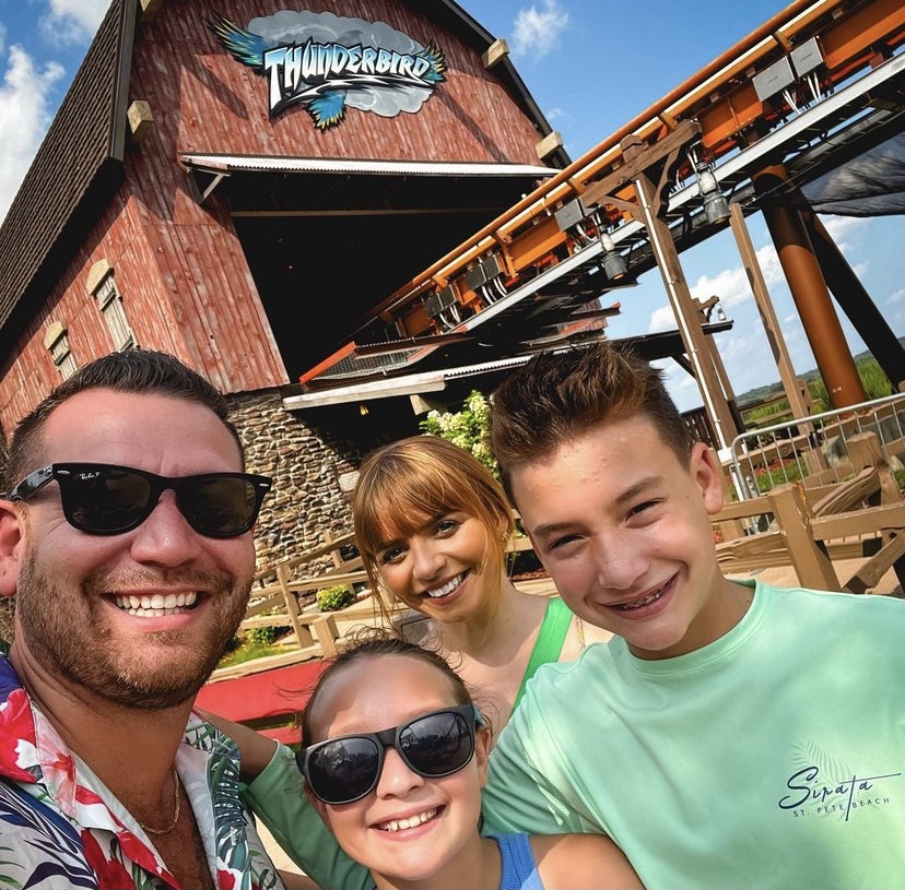 Family taking a selfie in front of the Thunderbird roller coaster