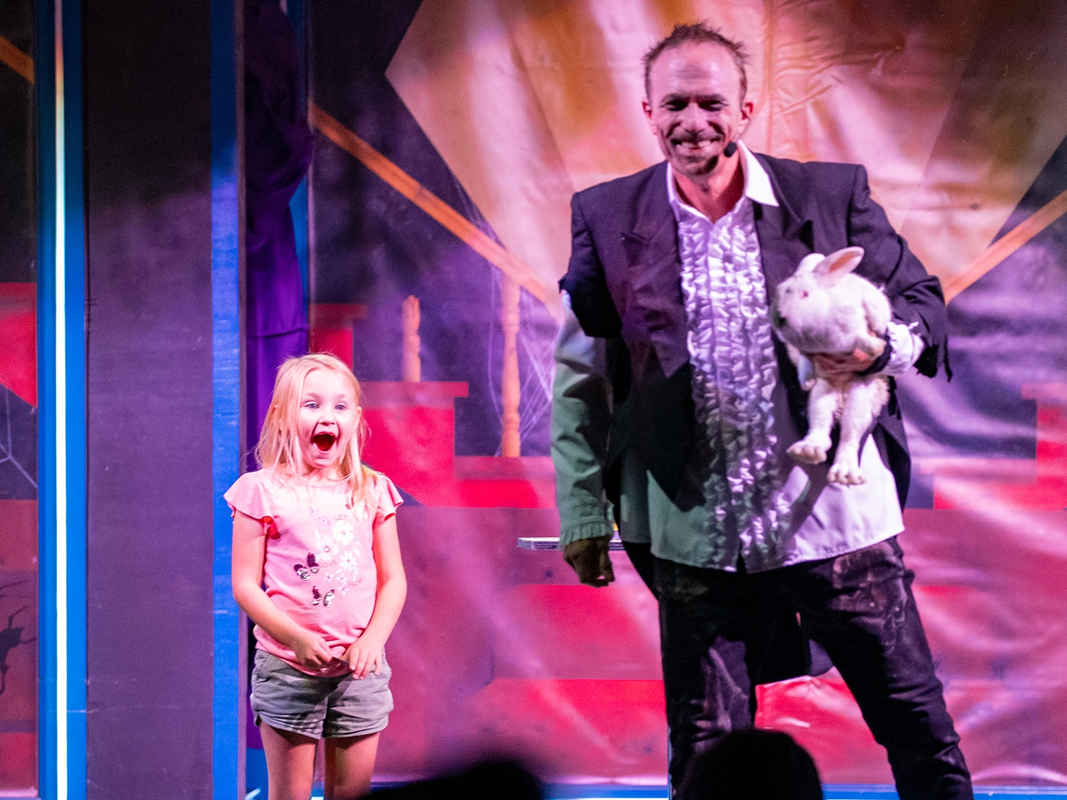 A young girl with a surprised expression at a rabbit that just magically appeared during Magic of the Night at Holiday World's Friday Night Live!