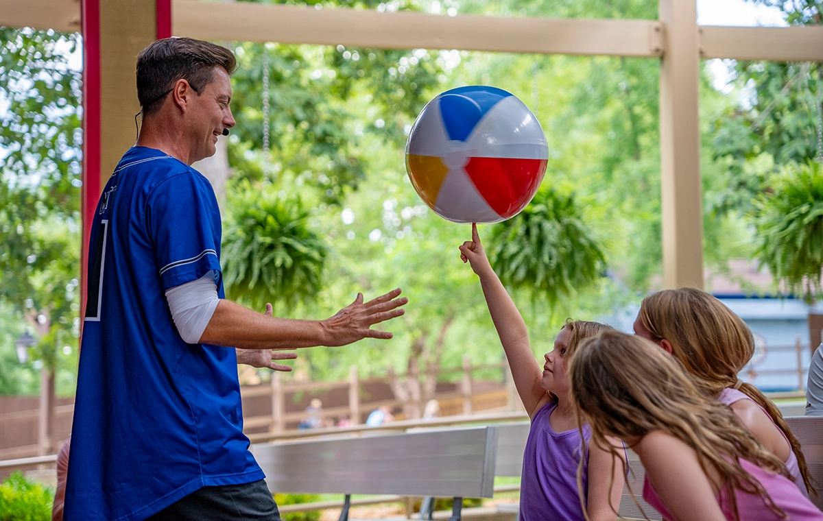 Matt Jergens helps a young girl balance a spinning beach ball on her finger during the Out of Hand Comedy Juggling Show at Holiday World.
