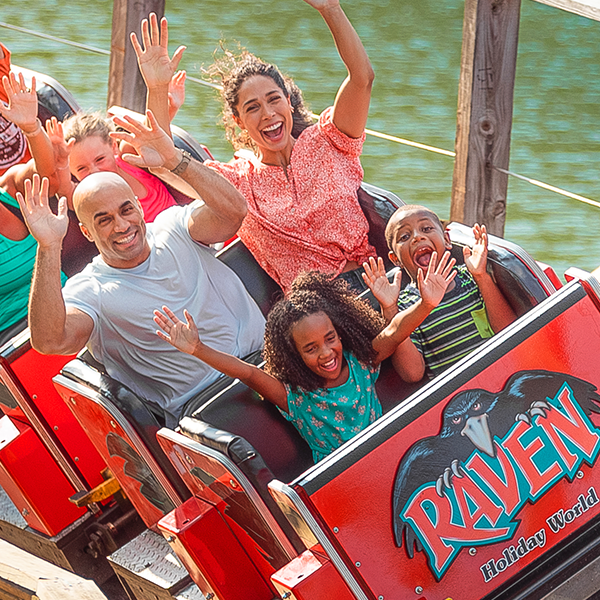 A family with their hands in the air rides Raven