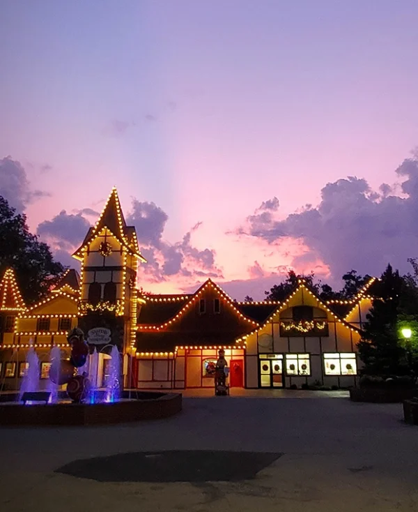 The sky is purple and pink as the sun rises behind Santa's Merry Marketplace