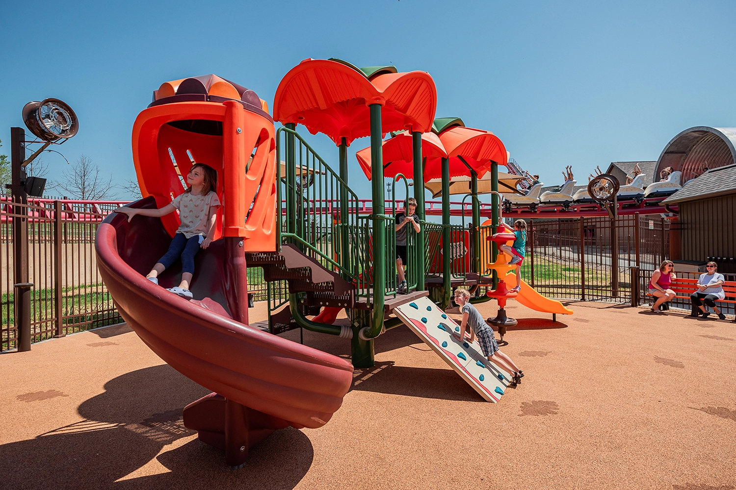 Children enjoying the Cranberry Corner playground as Good Gravy! Family Coaster passes by.