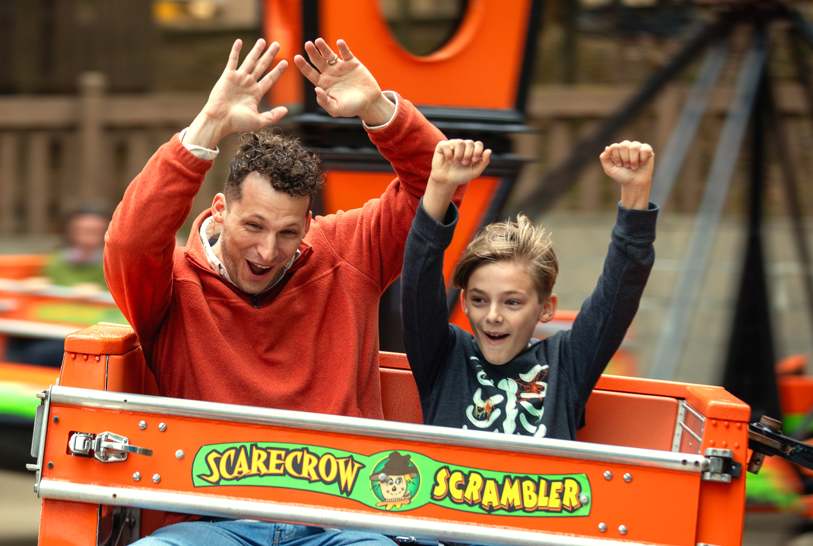 A father and son riding Scarecrow Scrambler during Happy Halloween Weekends